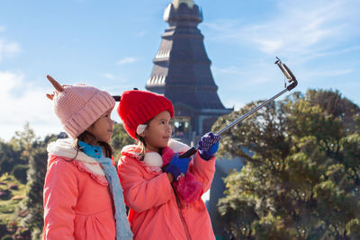 Cute siblings wearing warm clothing taking selfie in city