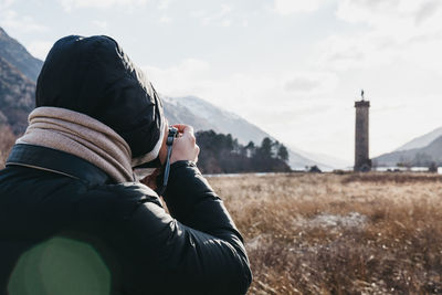 Midsection of woman photographing against sky