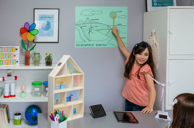 Student showing types of renewable energies in poster at ecology classroom