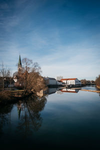 Buildings by river against blue sky