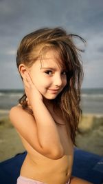 Portrait of shirtless girl sitting at shore of beach