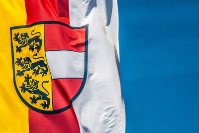 Low angle view of carinthia flag with coat of arms against blue sky