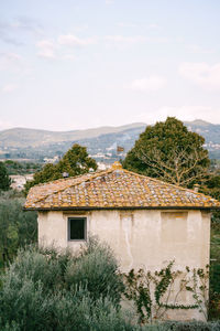 House and trees on landscape against sky