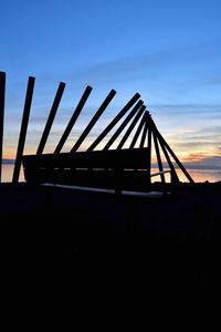 Silhouette bridge over sea against sky during sunset