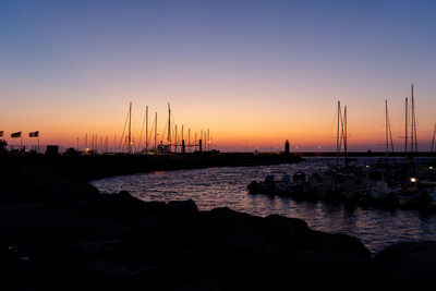 Silhouette sailboats in sea at sunset