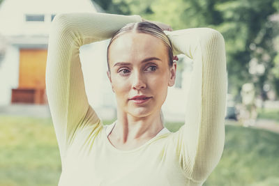 A young beautiful slender girl with long blonde hair does yoga in the summer in nature by the pond