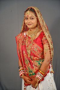 Portrait of smiling young bride standing against wall