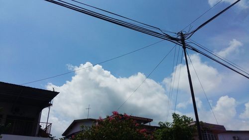 Low angle view of electricity pylon against cloudy sky