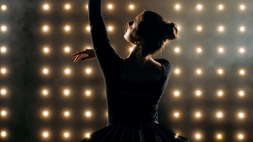 Ballerina dancing against illuminated lights