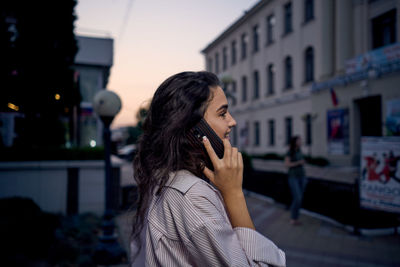 Young woman looking away while standing in city