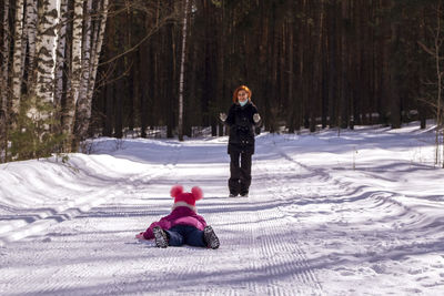 Mother playing with daughter on snow covered landscape