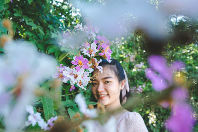 Portrait of smiling young woman by flowering plants