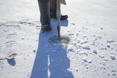 Low section of man walking on snow covered field