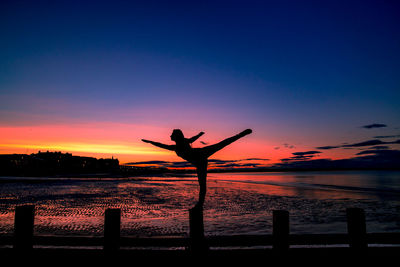 Silhouette man by sea against sky during sunset