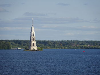 Sailboat on sea by building against sky