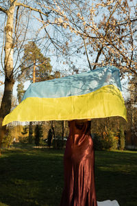 Rear view of woman with umbrella on field