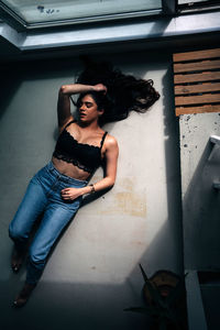 Portrait of young woman standing against wall