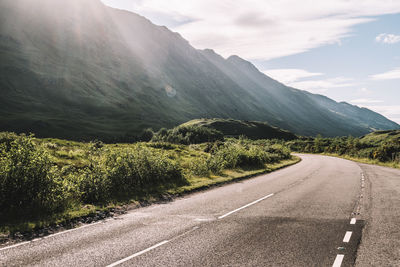 Road by mountains against sky
