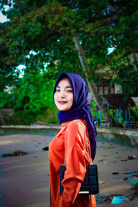 Portrait of smiling woman standing against trees