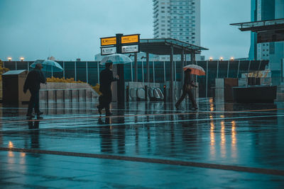 People walking with umbrellas in city street in rainy season