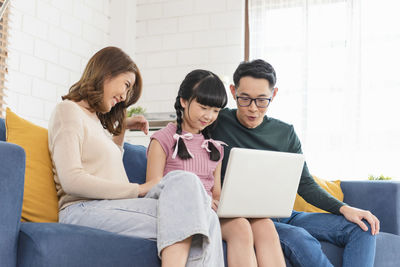 Friends sitting on sofa at home