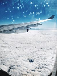 Airplane flying over snow against blue sky