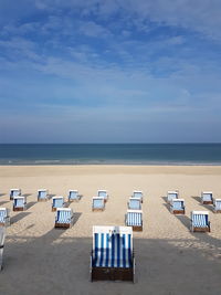 Deck chairs on beach against blue sky