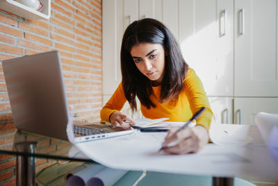 Young woman using phone while sitting on table