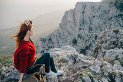 Woman sitting on rock against mountains