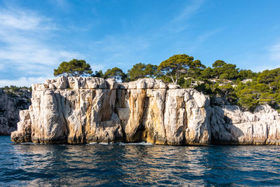 Rock formations by sea against blue sky