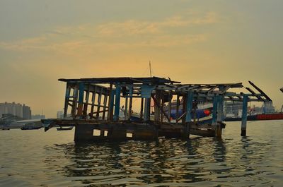 Ship moored in sea against sky during sunset