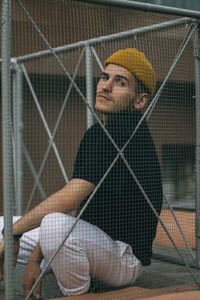 Portrait of man seen through chainlink fence