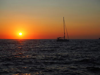 Silhouette sailboat in sea against sky during sunset