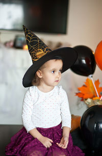 Cute girl looking away while wearing witch hat