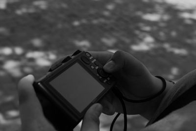 Cropped hands of man holding camera while standing on street