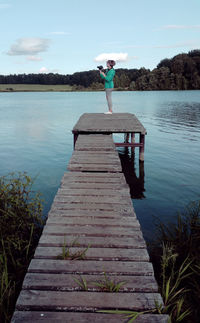 Teenage girl standing on pier at lake