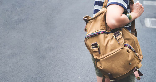 Midsection of woman with backpack standing on street