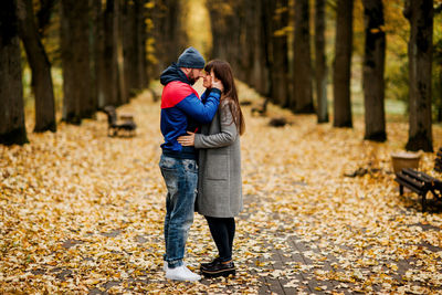 Two lovers are standing on an alley in an autumn park and hugging each other. autumn, love