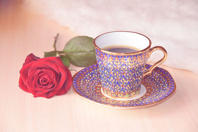 Thai traditional hand painting on tea and coffee cup set with red rose background 