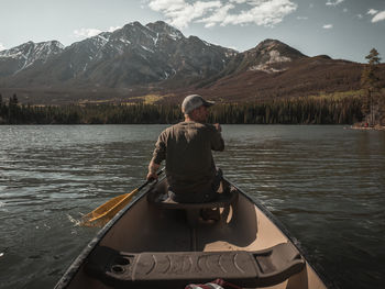 Rear view of man sitting on boat in lake