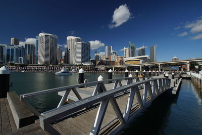 Bridge over river by buildings against sky in city