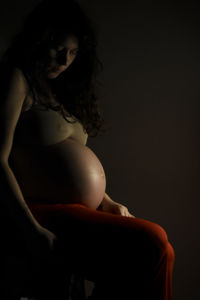 Midsection of woman sitting against black background