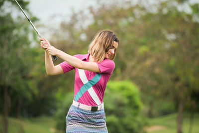 Young woman playing golf at course