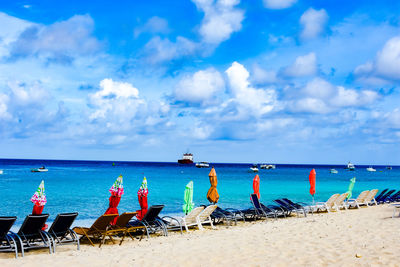 Chairs on beach against blue sky