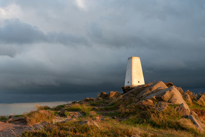 Lighthouse amidst rocks against sky