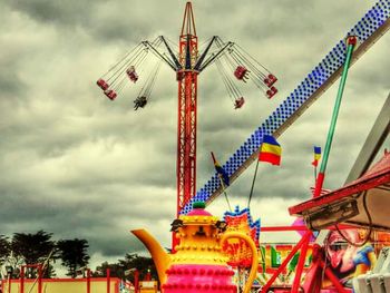 Low angle view of ferris wheel against cloudy sky