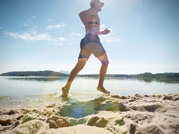 Man checking pulse trace on heartbeat monitor while running in water of lake. funy sport activities