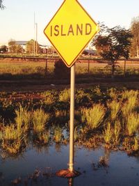 Information sign on countryside lake against sky