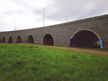 Arch bridge on field against sky