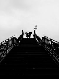 Low angle view of people on staircase against sky